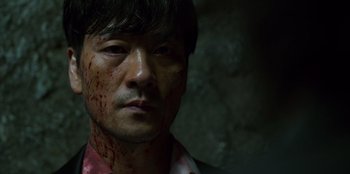 Movie still from “Squid Game” (2021), created by Hwang Dong-hyuk – A person with blood all over his face; Close Up shot, Low angle