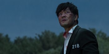 Movie still from “Squid Game” (2021), created by Hwang Dong-hyuk – A man with blood on his face is looking up at the sky; Close Up shot, Low angle