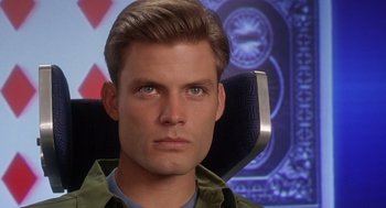 Movie still from “Starship Troopers” (1997), directed by Paul Verhoeven – A person sitting in a chair looking at the camera; Close Up shot, Over the shoulder angle
