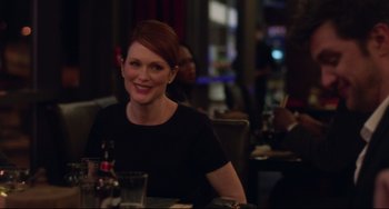 Movie still from “Still Alice” (2014), directed by Richard Glatzer – A woman sitting at a table with a glass in front of her; Medium shot, Over the shoulder angle