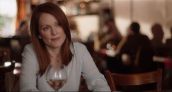 Movie still from “Still Alice” (2014), directed by Richard Glatzer – A woman sitting at a table holding a glass of wine; Close Up shot, Over the shoulder angle