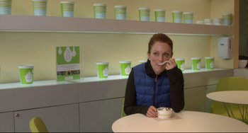 Movie still from “Still Alice” (2014), directed by Richard Glatzer – A woman sitting at a table with a bowl of yogurt in front of her mouth; Medium shot, Over the shoulder angle
