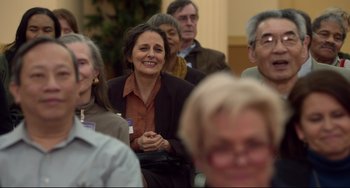 Movie still from “Still Alice” (2014), directed by Richard Glatzer – A group of people sitting and standing in a room; Medium shot, Over the shoulder angle
