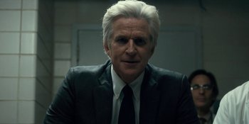 Movie still from “Stranger Things” (2016), created by Ross Duffer – An older man in a black suit and white shirt; Close Up shot, Over the shoulder angle