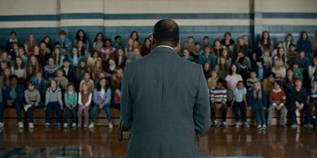 Movie still from “Stranger Things” (2016), created by Ross Duffer – A man standing in front of a group of people; Wide shot, Over the shoulder angle