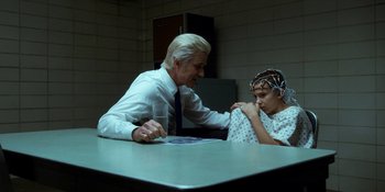 Movie still from “Stranger Things” (2016), created by Ross Duffer – A man sitting at a table next to a young boy; Medium shot, Over the shoulder angle