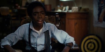 Movie still from “Stranger Things” (2016), created by Ross Duffer – A young man sitting in front of a camera in a living room; Close Up shot, Over the shoulder angle