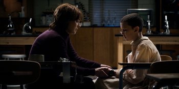 Movie still from “Stranger Things” (2016), created by Ross Duffer – A woman and a boy sitting in a room; Medium shot, Over the shoulder angle