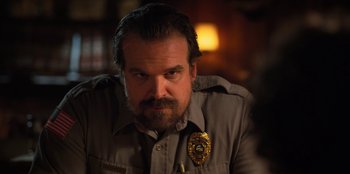 Movie still from “Stranger Things” (2016), created by Ross Duffer – A person wearing a police uniform; Close Up shot, Over the shoulder angle