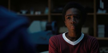 Movie still from “Stranger Things” (2016), created by Ross Duffer – A young man sitting in front of a window; Close Up shot, Over the shoulder angle