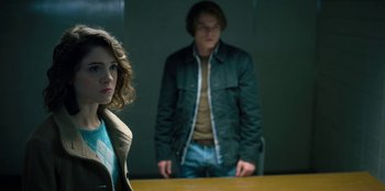 Movie still from “Stranger Things” (2016), created by Ross Duffer – A man and a woman standing next to each other in a room; Medium shot, Over the shoulder angle