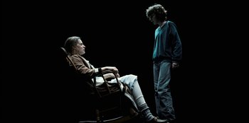 Movie still from “Stranger Things” (2016), created by Ross Duffer – A man standing next to a woman in a rocking chair; Wide shot, High angle