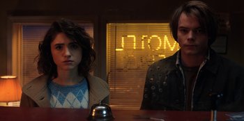Movie still from “Stranger Things” (2016), created by Ross Duffer – A man and a woman standing next to each other at a counter; Medium shot, Low angle