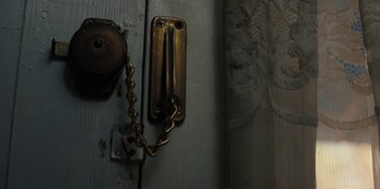 Movie still from “Stranger Things” (2016), created by Ross Duffer – A door handle with a chain attached; Extreme Close Up shot, High angle