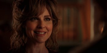 Movie still from “Stranger Things” (2016), created by Ross Duffer – A woman smiling for the camera; Close Up shot, Over the shoulder angle