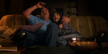 Movie still from “Stranger Things” (2016), created by Ross Duffer – A man and a woman sitting next to each other on a couch; Medium shot, Overhead angle