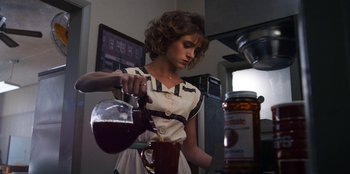 Movie still from “Stranger Things” (2016), created by Ross Duffer – A woman pouring a cup of liquid into a glass; Medium shot, Low angle