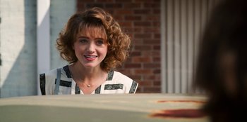 Movie still from “Stranger Things” (2016), created by Ross Duffer – A beautiful woman with curly red hair sitting at a table; Close Up shot, Over the shoulder angle