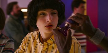 Movie still from “Stranger Things” (2016), created by Ross Duffer – A woman is putting makeup on her face; Close Up shot, Over the shoulder angle