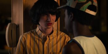 Movie still from “Stranger Things” (2016), created by Ross Duffer – A young man in a striped shirt is talking to a young man; Close Up shot, Over the shoulder angle