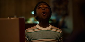 Movie still from “Stranger Things” (2016), created by Ross Duffer – A young boy with his mouth wide open looking up; Close Up shot, Low angle
