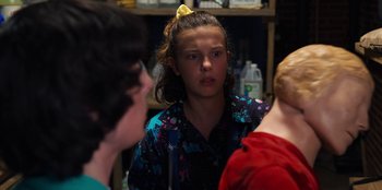 Movie still from “Stranger Things” (2016), created by Ross Duffer – A young girl with a yellow bow in her hair; Close Up shot, Over the shoulder angle