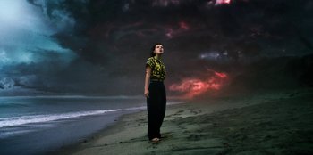 Movie still from “Stranger Things” (2016), created by Ross Duffer – A woman standing on the beach in front of a cloudy sky; Extreme Wide shot, Low angle
