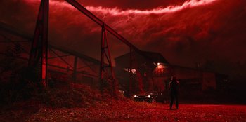 Movie still from “Stranger Things” (2016), created by Ross Duffer – A person standing in front of an abandoned building; Extreme Wide shot, Low angle