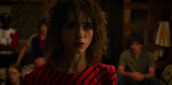 Movie still from “Stranger Things” (2016), created by Ross Duffer – A young woman in a red and black striped shirt; Close Up shot, Over the shoulder angle