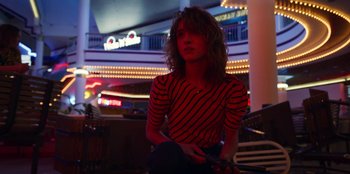 Movie still from “Stranger Things” (2016), created by Ross Duffer – A person sitting on the ground in a room; Medium shot, Low angle