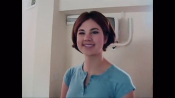 Movie still from “Strip Down, Rise Up” (2021), directed by Michèle Ohayon – A woman in a blue shirt smiles for the camera; Medium shot, Low angle
