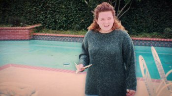Movie still from “Strip Down, Rise Up” (2021), directed by Michèle Ohayon – A woman standing in front of a swimming pool; Medium shot, High angle