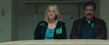 Movie still from “Stronger” (2017), directed by David Gordon Green – A woman sitting in front of a table with other people; Medium shot, Over the shoulder angle