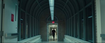 Movie still from “Stronger” (2017), directed by David Gordon Green – A man walking down a hall way in a building; Wide shot, Low angle