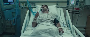 Movie still from “Stronger” (2017), directed by David Gordon Green – A man laying in a hospital bed holding a pair of scissors; Medium shot, High angle