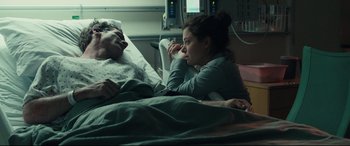 Movie still from “Stronger” (2017), directed by David Gordon Green – A man laying in a hospital bed next to a woman; Medium shot, Over the shoulder angle