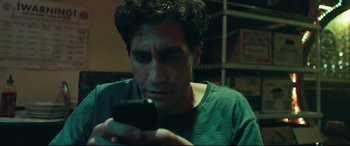 Movie still from “Stronger” (2017), directed by David Gordon Green – A man looking at his cell phone while sitting in a room; Close Up shot, Low angle