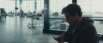 Movie still from “Stronger” (2017), directed by David Gordon Green – A man sitting in front of a window looking at a phone; Medium shot, Over the shoulder angle
