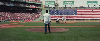 Movie still from “Stronger” (2017), directed by David Gordon Green – A man in a white shirt is holding a baseball bat on a baseball field; Extreme Wide shot, High angle