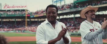 Movie still from “Stronger” (2017), directed by David Gordon Green – A man wearing a white shirt clapping his hands in front of a crowd; Medium shot, Over the shoulder angle