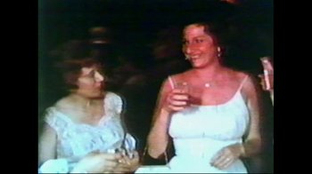 Movie still from “Studio 54” (2018), directed by Matt Tyrnauer – Two women are smiling and drinking wine; Medium shot, High angle