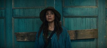 Movie still from “Sweet Tooth” (2021), created by Jim Mickle – A woman wearing a hat standing in front of a wooden door; Close Up shot, Low angle
