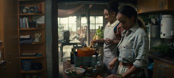 Movie still from “Sweet Tooth” (2021), created by Jim Mickle – A group of people standing in a kitchen preparing food; Medium shot, Over the shoulder angle