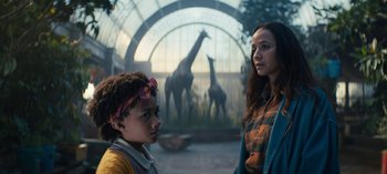 Movie still from “Sweet Tooth” (2021), created by Jim Mickle – Two young girls standing next to each other in front of giraffes; Medium shot, Low angle