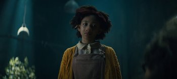 Movie still from “Sweet Tooth” (2021), created by Jim Mickle – A young girl in a yellow sweater and brown overalls stands in a dimly - lit room; Close Up shot, Low angle