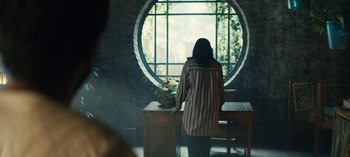 Movie still from “Sweet Tooth” (2021), created by Jim Mickle – A woman standing in front of a round window; Wide shot, Over the shoulder angle