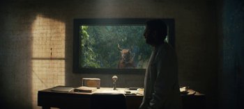 Movie still from “Sweet Tooth” (2021), created by Jim Mickle – A man standing in front of a large screen tv; Medium shot, Over the shoulder angle