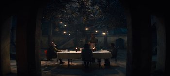 Movie still from “Sweet Tooth” (2021), created by Jim Mickle – A group of people sitting around a table at night; Wide shot, High angle