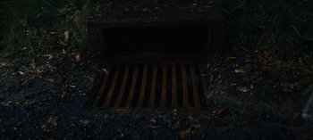 Movie still from “Sweet Tooth” (2021), created by Jim Mickle – A metal grate on the side of the road; Extreme Close Up shot, Overhead angle