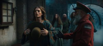 Movie still from “Sweet Tooth” (2021), created by Jim Mickle – A group of people standing around a building; Medium shot, Over the shoulder angle